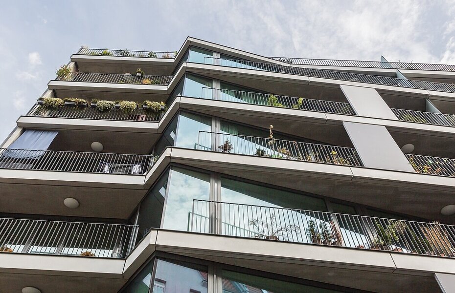 Balkonfassade des Wohnprojekts PolygonGarden in Berlin-Friedrichshain mit gestaffelten Balkonen, großen Fenstern und Pflanzungen